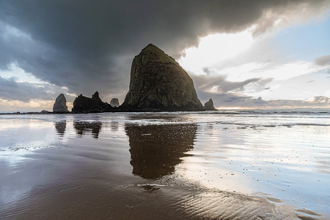 Haystack Rock at Cannon Beach under storm light, reflected in wet sand