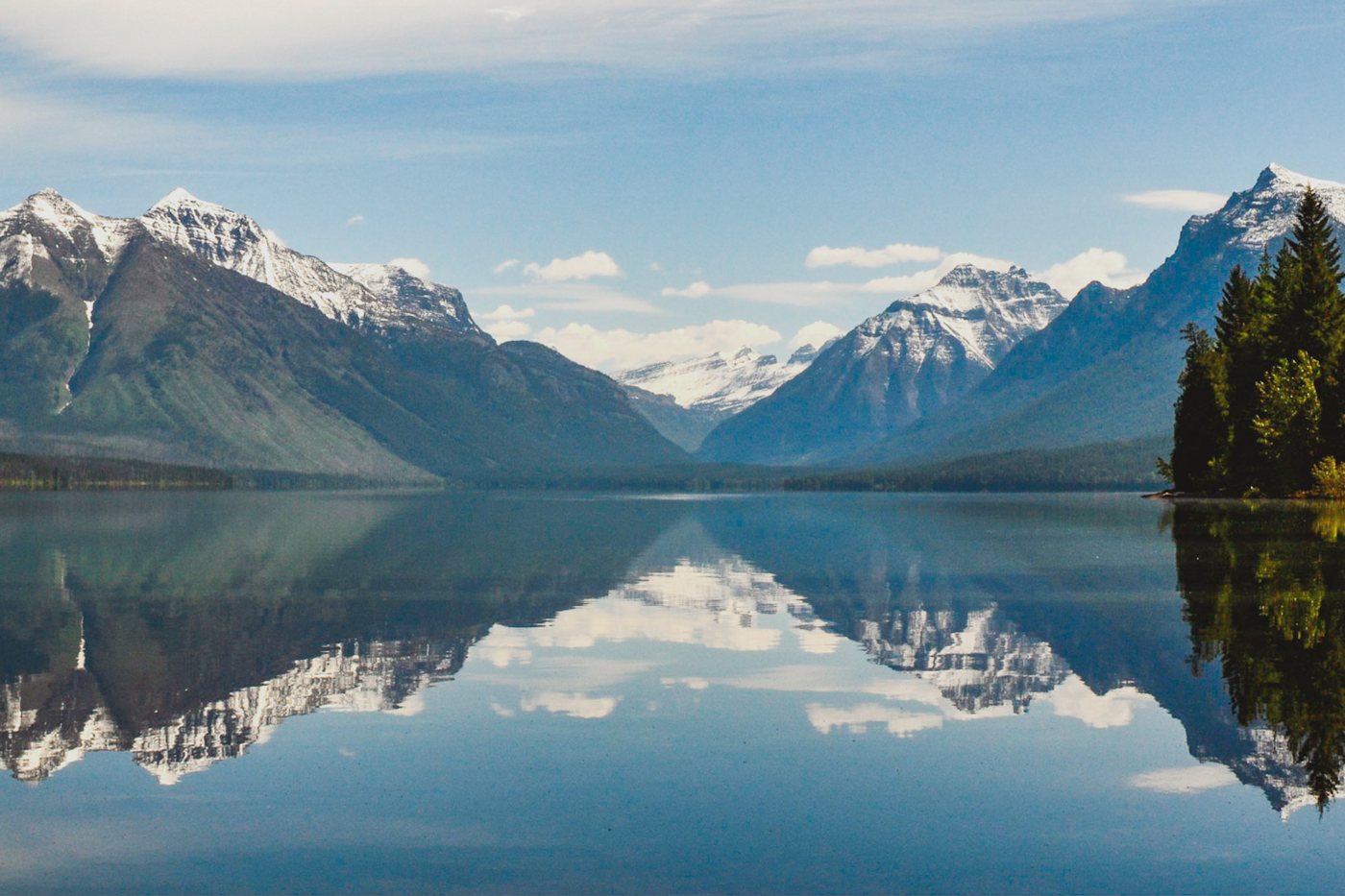 Snow-capped peaks mirrored in the still surface of Lake McDonald, Glacier