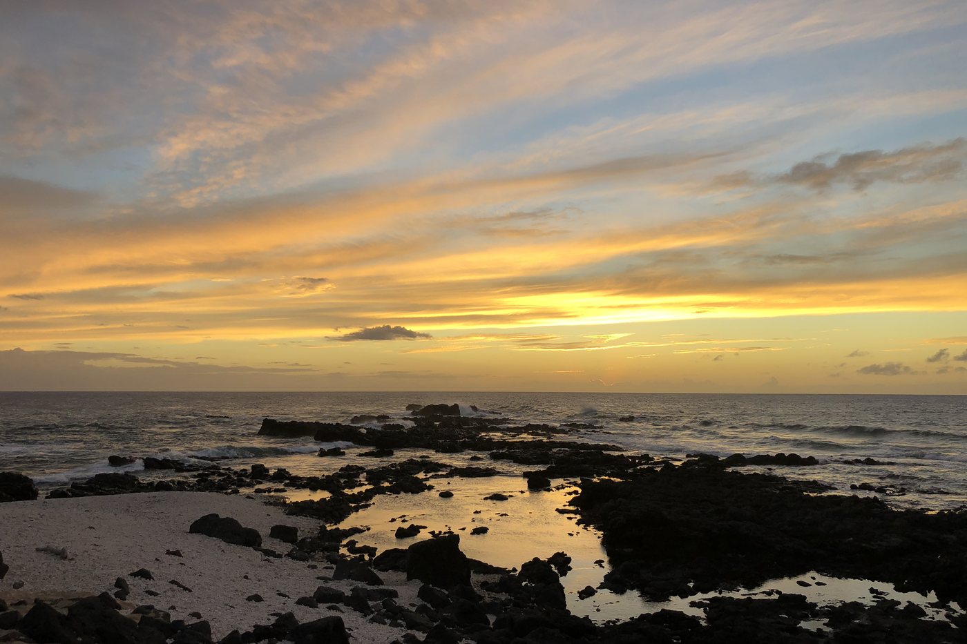 Sunset over tidepools and lava rock on a Hawaiian shore